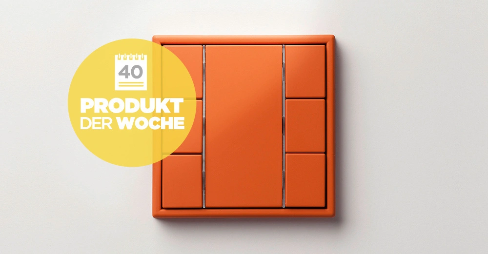 Orangener Lichtschalter an einer weißen Wand mit einem gelben Kreis neben dem Schalter Text im Kreis 40 PRODUKT DER WOCHE.