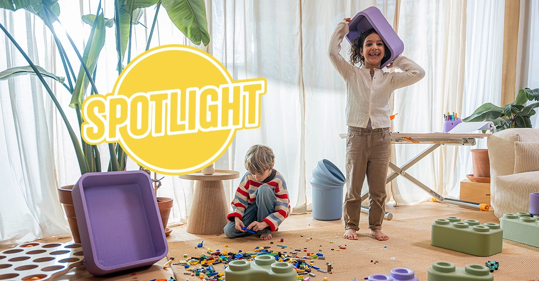 Mädchen und Junge spielen in großem, hellem Kinderzimmer mit Legos und den bunten Aufbewahrungsboxen