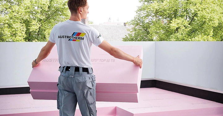 Austrotherm Mitarbeiter von hinten trägt rosa Dämmplatten