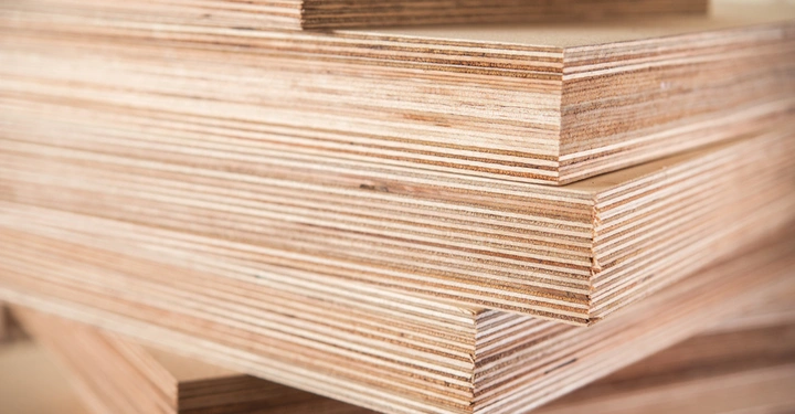 Holzplatten liegen gestapelt übereinander in einem gut beleuchteten Innenraum.