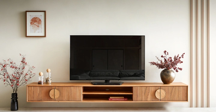 Fernseher auf einem hölzernen Fernsehschrank in einem Wohnzimmer Zwei Vasen mit roten Beeren und eine gerahmte Kunstwerk hängen an der Wand