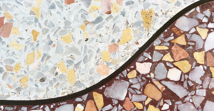 Terrazzoboden in zwei Farbvarianten: helle und dunkle Muster aus verschiedenfarbigen Fliesen und Steinfragmenten miteinander verbunden durch eine leicht geschwungene Linie im Bildzentrum.