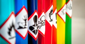 Reagenzgläser enthalten farbige Flüssigkeiten stehen nebeneinander Warnaufkleber mit Symbolen für verschiedene Gefahren wie giftig ätzend und entzündlich Kontext Labor oder chemische Umgebung