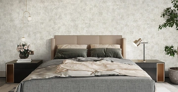 Doppelbett steht ordentlich in einem modernen Schlafzimmer umgeben von zwei Nachttischen einem Strauß Blumen einer Tischlampe und einer Zimmerpflanze vor einer dezent gemusterten Wand.