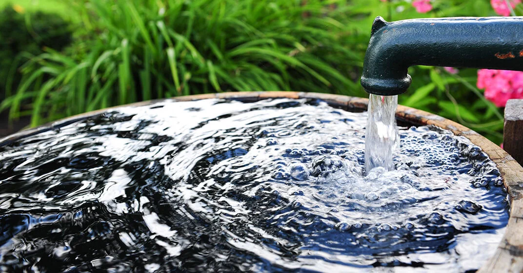 Wasserstelle in Garten: Brunnen führt Wasser in Tonne