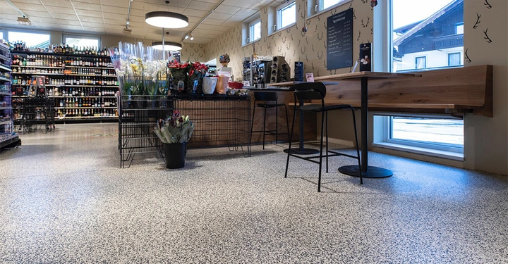 Galerie-Bild 3: Blumen und Getränke ruhig in einem gut beleuchteten Geschäft auf Regalen und Tischen präsentiert industrielle Einrichtung. Ein schwarzes Schild an der Wand neben den Fenstern zeigt Menüpunkte