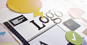 Papierausschnitte in verschiedenen Farben und Formen liegen auf einem Tisch Action Design-Elemente und Werkzeuge sind verstreut Context Logo-Designprozess Text Logo Design