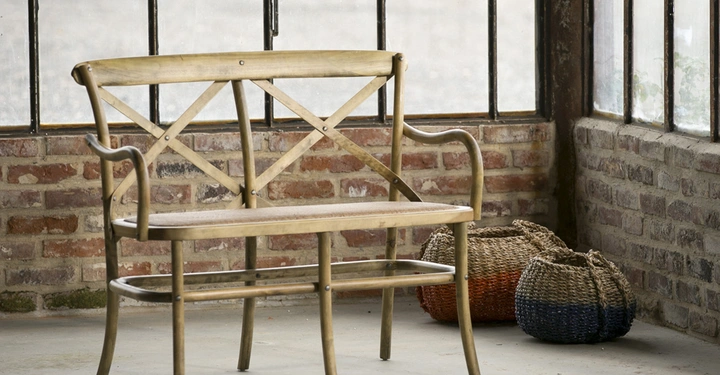 Galerie-Bild 9: Holzbank steht still im Raum Ecke umgeben von großen Fenstern und Ziegelwänden dekoriert mit zwei geflochtenen Körben auf dem Boden links.