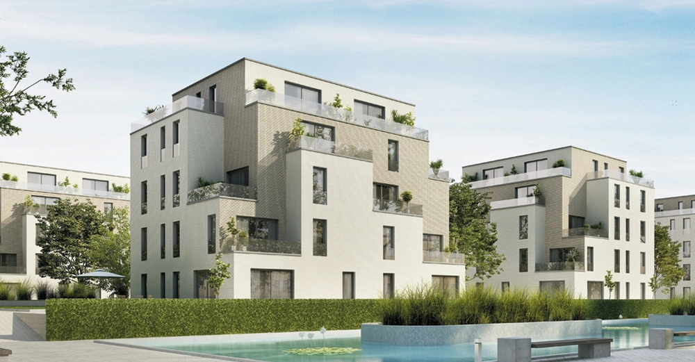 moderner Wohnblock mit unterschiedlichen Geschoßhöhen, Vorsprüngen und Balkonen vor großem angelegten See. Sommerlicher Eindruck.