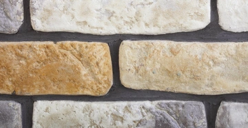 Mehrfarbige rechteckige Mauersteine horizontal angeordnet eingebettet in dunkelgrauen Mörtel in gemischtem Farbmuster.