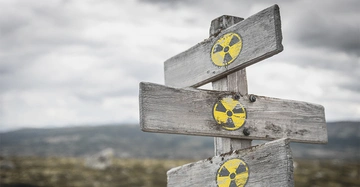 Holzschilder zeigen das radioaktive Warnzeichen in gelben und schwarzen Farben Berglandschaft verschwommen im Hintergrund bewölkter Himmel