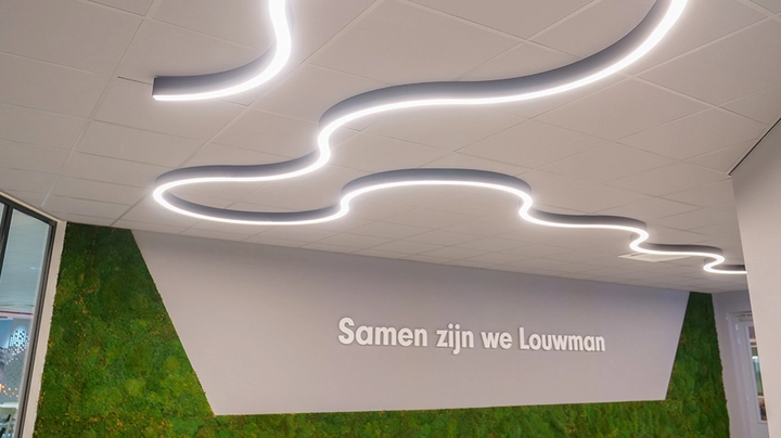 Galerie-Bild 2: Geschlängelte Lichtlinien an einer Bürodecke, darunter Firmenmotto "Samen zijn we Louwman" - zusammen sind wir Louwman.
