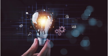 Eine Hand hält eine Glühbirne vor einem dunklen Hintergrund mit Symbolen, die für Ideen und Digitalisierung stehen.