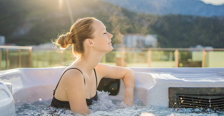 Frau entspannt im sprudelnden Outdoor-Whirlpool vor Bergkulisse. Überblick über Whirlpool-Modelle, Ausstattung, Technik und Preise für die private Nutzung im Garten.