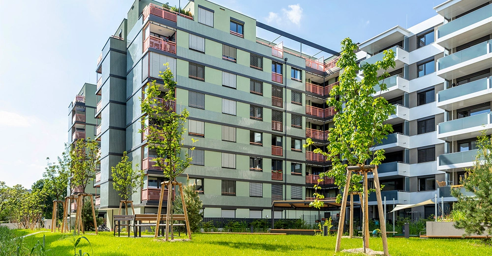 Detaildarstellung des Wohngebäudes Orchidea aus Kennedy Garden, im Vordergrund ein grüner Innenhof mit Rasen und Bäumen