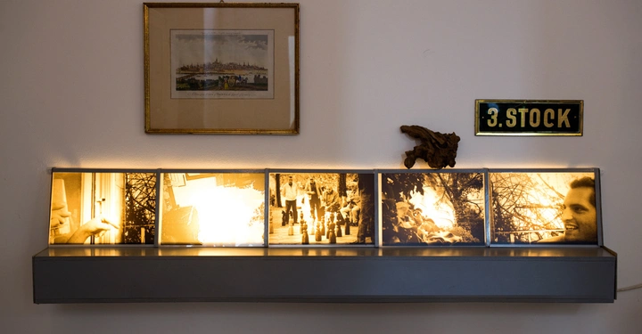 Galerie-Bild 5: Leuchtkasten mit fünf beleuchteten Fotografien stehend auf einem Regal an einer Wand im Hintergrund ein gerahmtes Bild ein Wandschild mit der Aufschrift 3.STOCK und ein kleines hölzernes Objekt