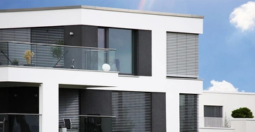 Neubau: Apartmentgebäude mit weißem Fassadenanstrich und dunklen Jalousien
