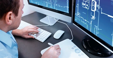 Eine Person arbeitet am Computer und erstellt technische Zeichnungen auf zwei Monitoren. Der Kontext ist ein modernes Büro oder Arbeitsplatz mit Tastatur und Zeichentablett.