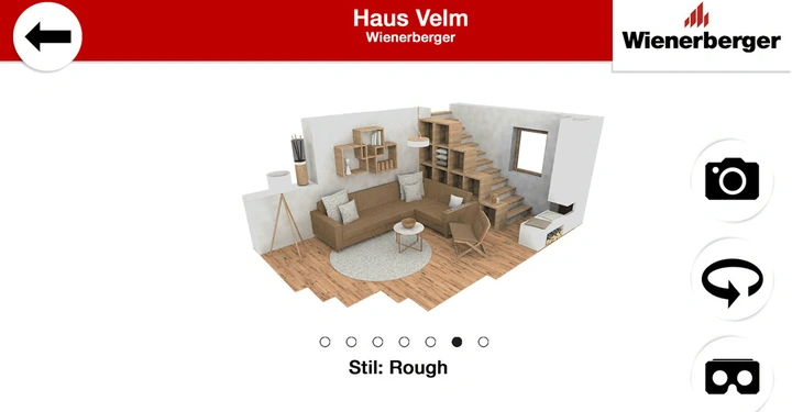 Wohnzimmer mit braunem Sofa, Couchtisch und Regalen aus Holz links brennender Kamin rechts Holztreppe im offenen Raum. Stil Rough. Text Haus Velm Wienerberger links Pfeilsymbol rechts Kamera Symbol.