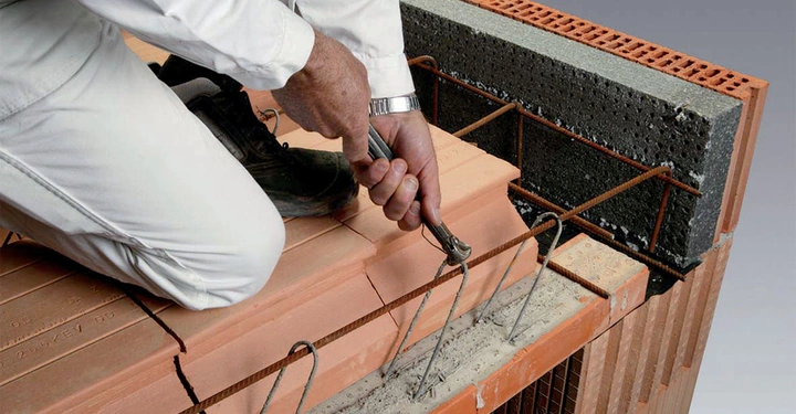 Arbeiter in weißem Overall hängt mit Kappeisen Füllziegel in Einhängedecke