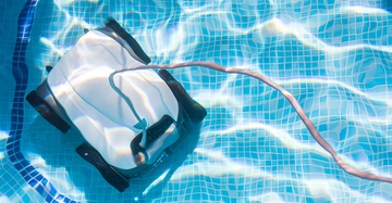 Blick von oben in das Poolwasser, wo ein Saugroboter am Beckenboden seine Arbeit macht. Es scheint die Sonne, sie reflektiert im Wasser.