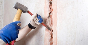 Stemmarbeiten werden mit Hammer und Meißel an einer Wand durchgeführt.