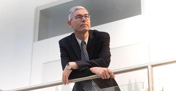 Mann lehnt an Geländer Bürogebäude helle Umgebung