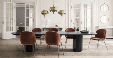 Ovaler schwarzer Esstisch stehend in einem eleganten weißen Raum umgeben von sechs braunen Stühlen drei hängenden goldenen Lampen und hohen Doppelflügeltüren im Hintergrund dekorative Wanddetails