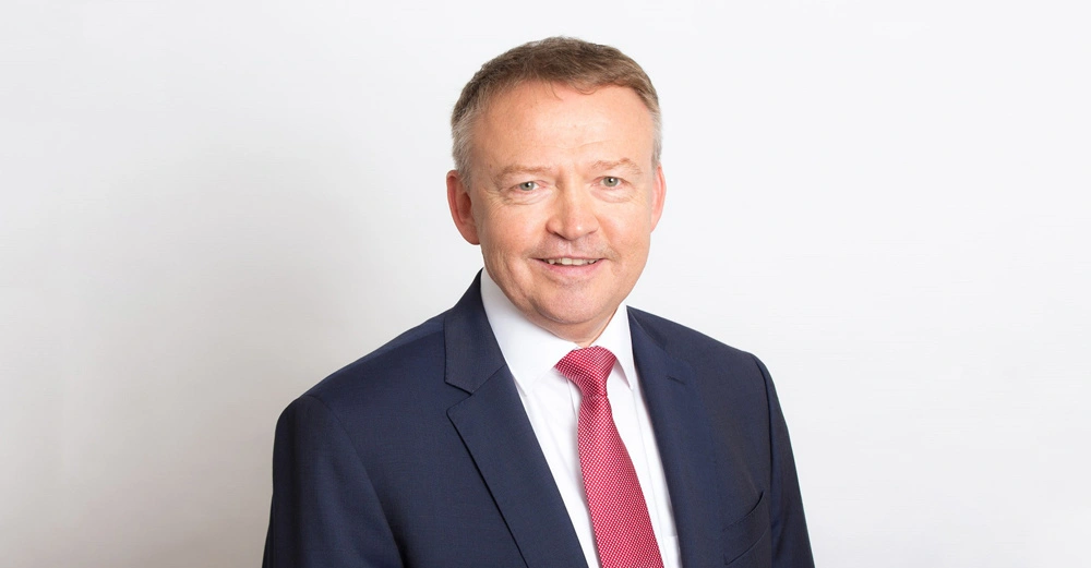 Mann lächelt Weißes Hemd und roter Krawatte Dunkler Anzug Hintergrund ist weiß und schlicht