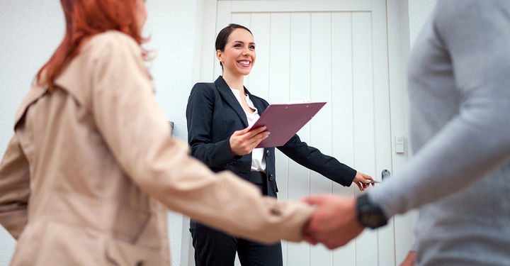 Ein Paar beginnt die Immobiliensuche mit einer Maklerin. Die anfallende Maklerprovision wird nach erfolgreichem Kaufabschluss fällig.