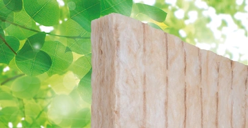 Dämmplatte in vertikaler Position vor verschwommenem Hintergrund mit grünen Blättern und hellem Licht.