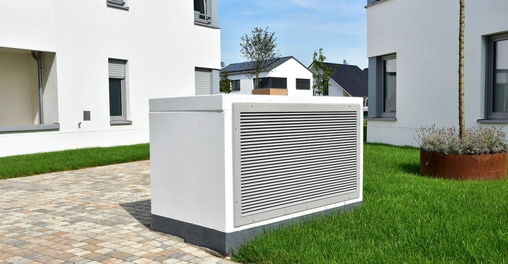 Außengerät einer modernen, kontrollierten Wohnraumlüftung vor einem Neubau, das für eine konstant gute Raumluft und frische Luft sorgt.