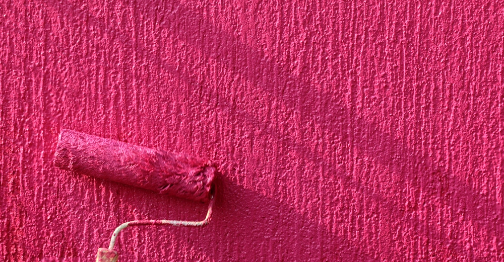 Innenwand mit Malerrolle in Großaufnahme, knalliges Magenta, Silikatfarbe
