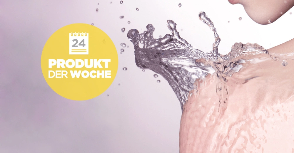 Wasser spritzt auf eine nackte Schulter in einem minimalistisch gestalteten Raum linkerseits befindet sich ein gelber Kreis mit der weißen Aufschrift 24 Produkt der Woche
