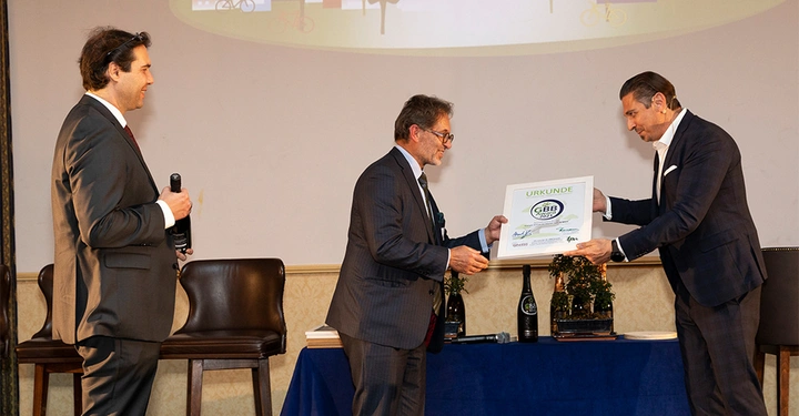 Galerie-Bild 5: Zwei Männer in Anzügen überreichen eine Urkunde miteinander Bühne im Hintergrund ein dritter Mann hält eine Flasche Text: URKUNDE GBB The Green and Blue Building Zertifikat Chillventa 2022 Logo: GBB Green and Blue Building