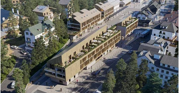 Luftaufnahme eines großen Hotels aus Holz mit vorgelagerten Terrassen und länglichem Baukörper.