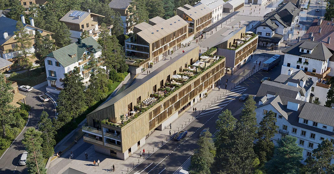 Luftaufnahme eines großen Hotels aus Holz mit vorgelagerten Terrassen und länglichem Baukörper.