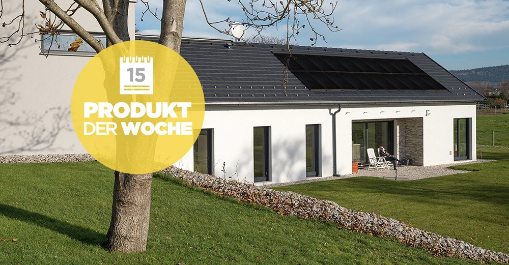 Baum steht still auf grünem Rasen vor modernem weißem Haus mit großen Fenstern und Solarpanelen auf dem Dach in ländlicher Umgebung Text: 15 Produkt der Woche