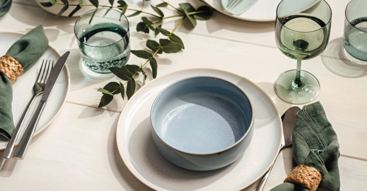 Eine hellblaue Schale (Crafted Breeze) steht auf einem cremefarbenen Teller der Serie Crafted Cotton von Villeroy & Boch.