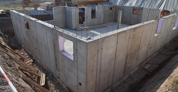 Betonstruktur im Bau stehend auf einer Baustelle umgeben von Baumaterialien und Erdreich.