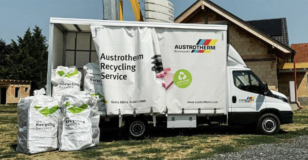 Kleinlastwagen von Austrotherm steht auf Baustelle. Mehrere Säcke mit Dämmresten stehen vor der Ladefläche.