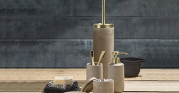 Eine Gruppe von Badezimmer-Accessoires aus grauem Material steht auf einem Holzuntergrund vor einer dunkelgrauen Wand. Enthält Zahnbürsten, Seifenspender, Toilettenbürste, Seifenstück und Wattestäbchen.