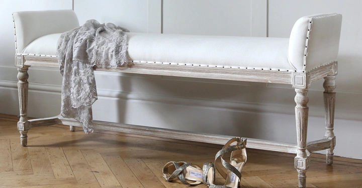 Galerie-Bild 5: Eine weiße Bank steht im eleganten Raum mit hellem Holzboden. Ein graues Tuch liegt darauf und glitzernde High Heels stehen davor.