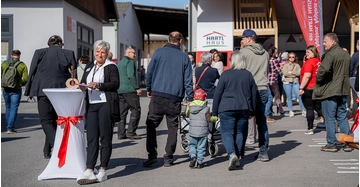 zahlreiche Besucher, Menschen mit Kinderwagen, alte Personen und eine Frau an Stehtisch bei Veranstaltung unter freiem Himmel