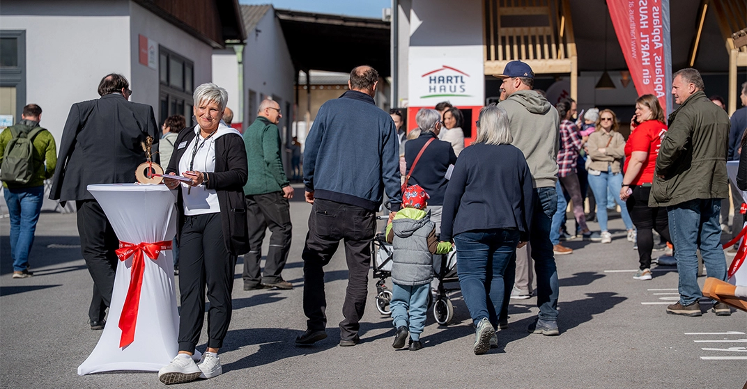 zahlreiche Besucher, Menschen mit Kinderwagen, alte Personen und eine Frau an Stehtisch bei Veranstaltung unter freiem Himmel