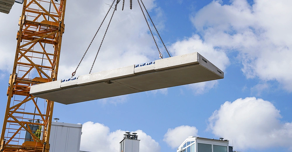 Just-in-time auf der Baustelle: Die Balkonplatte wird als Fertigteil an die Baustelle geliefert und mittels eines Krans zur jeweiligen Anschlussstelle des Gebäudes gehoben. Der deckenseitige Part von Schöck Isokorb IQ Typ K wurde vorab im Gebäude verbaut. Im Bild: Projekt Seidengasse 32 im 7. Wiener Gemeindebezirk der OBENAUF Immobilienentwicklung GmbH.