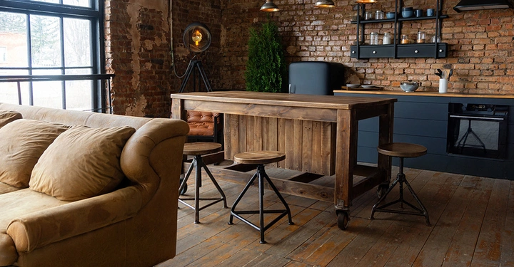 Loft im Industriestyle mit braunem Sofa und schwarzer Küche mit Kücheninsel