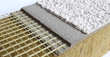 Querschnitt eines Wärmedämmverbundsystems mit Steinwolle als Dämmung, einer Armierschicht und einen groben weißen Oberputz.