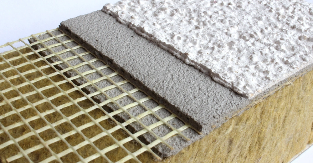 Querschnitt eines Wärmedämmverbundsystems mit Steinwolle als Dämmung, einer Armierschicht und einen groben weißen Oberputz.