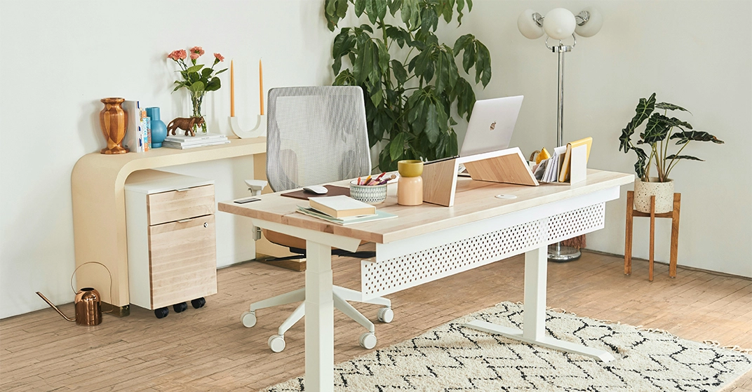 Helles Homeoffice mit modernem, höhenverstellbarem Schreibtisch aus Holz und Weiß, ergonomischem Bürostuhl, Laptop, dekorativen Pflanzen, Sideboard und Teppich in gemütlicher Wohnatmosphäre.